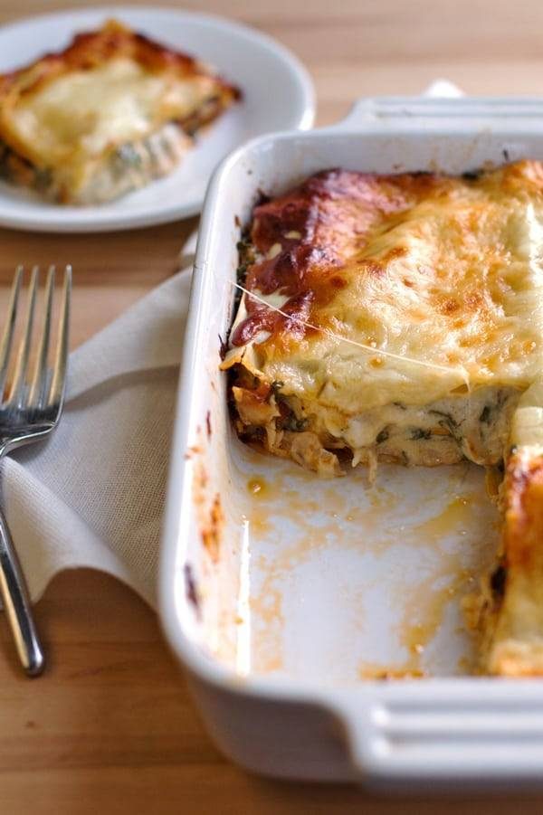 Chicken Caesar Lasagna in a white baking dish and a fork.