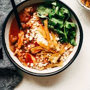 Chicken Tortilla Soup in a bowl with toppings and a spoon.