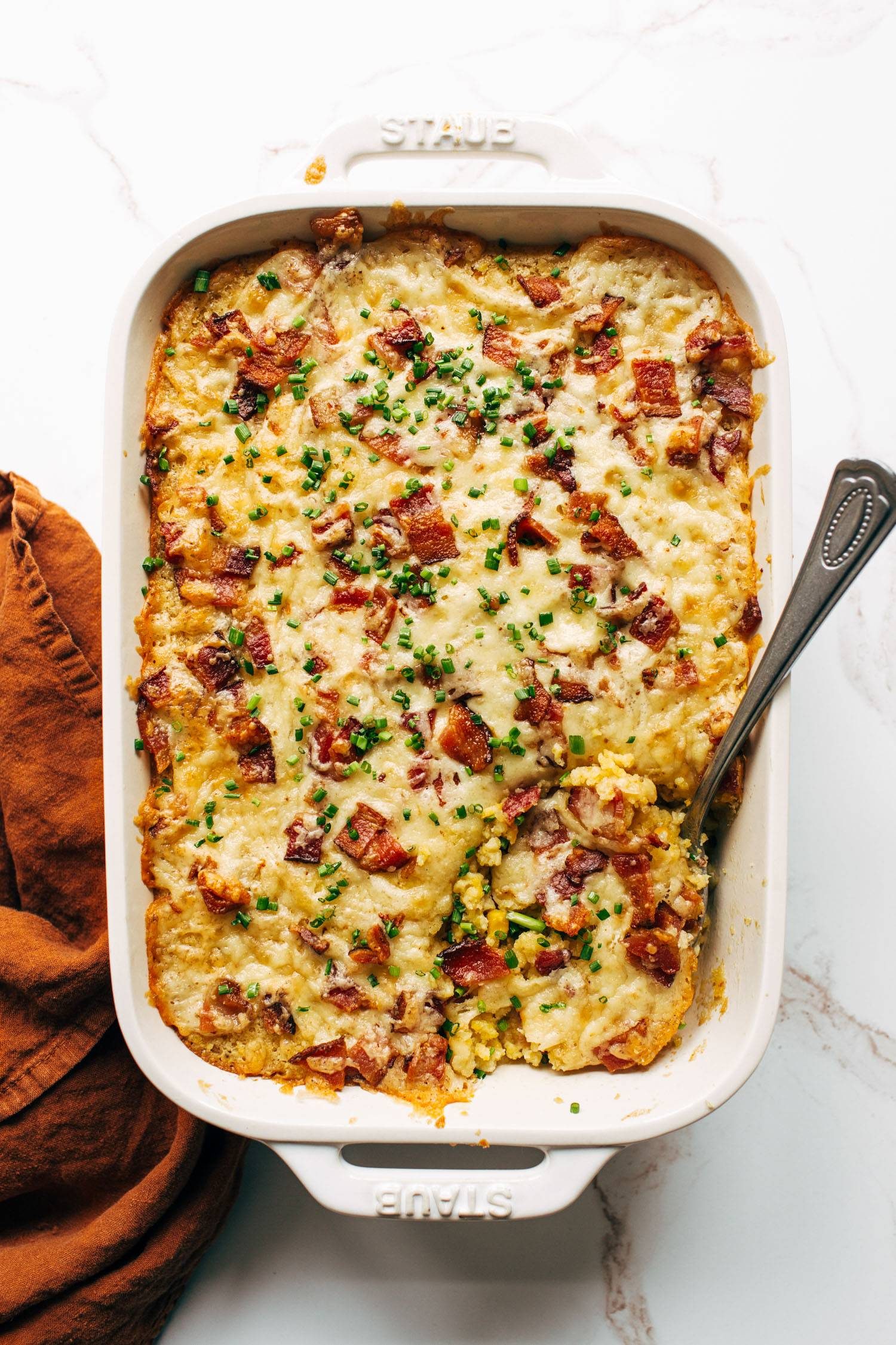 Corn casserole in a casserole dish with a serving spoon.