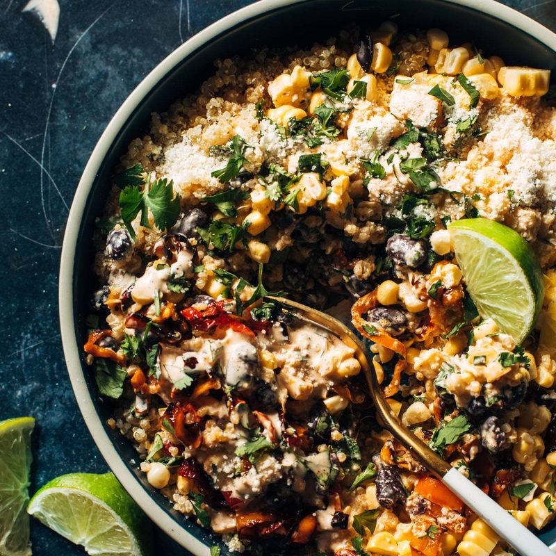 Elote quinoa salad in a bowl with cotija cheese and a fork