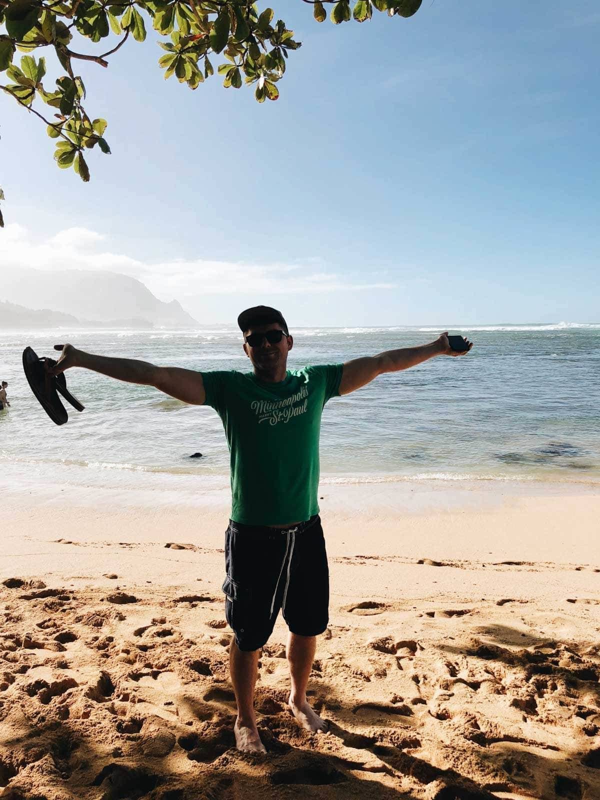 Man with his arms spread on the beach.