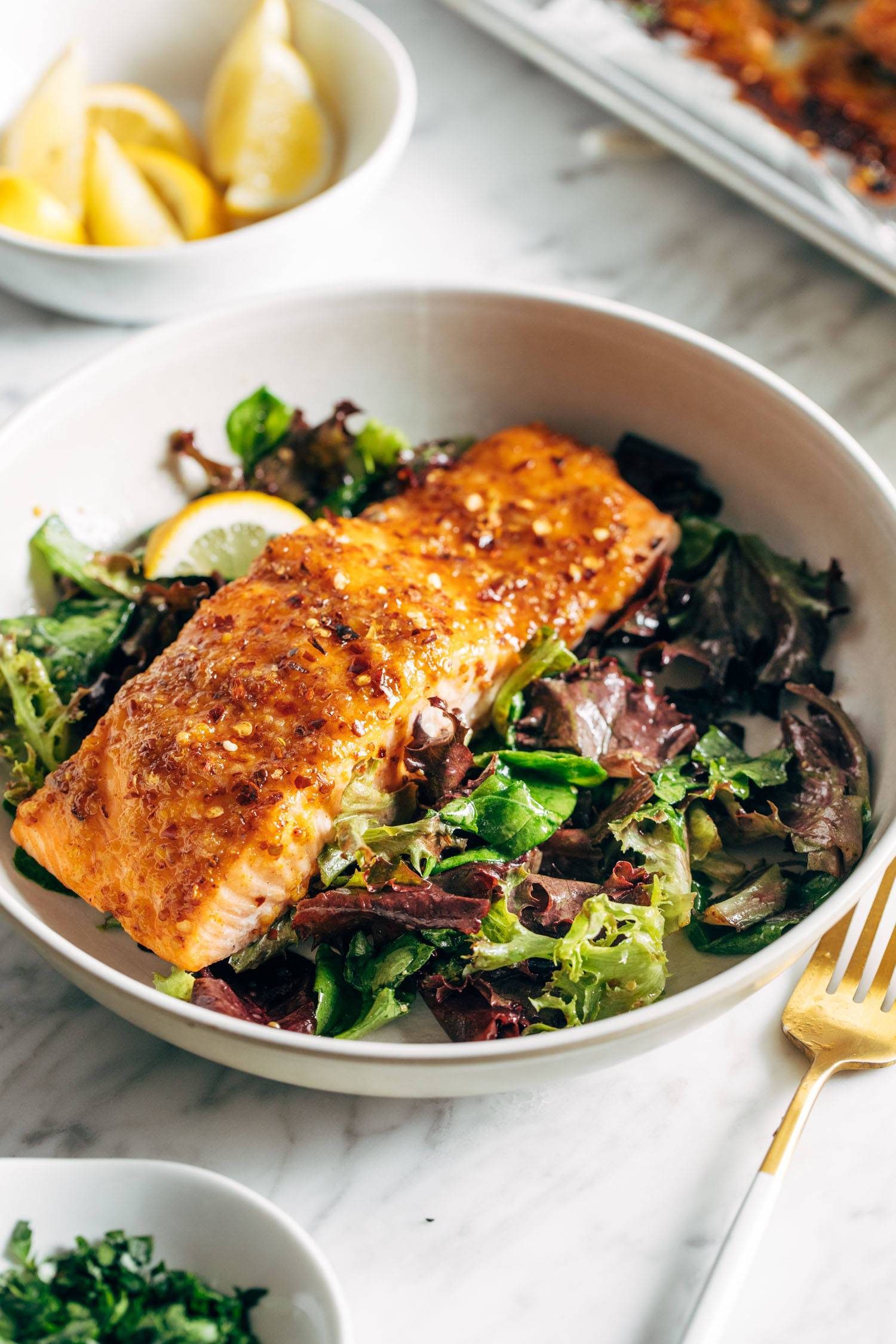 Hot honey salmon in a bowl with green salad.