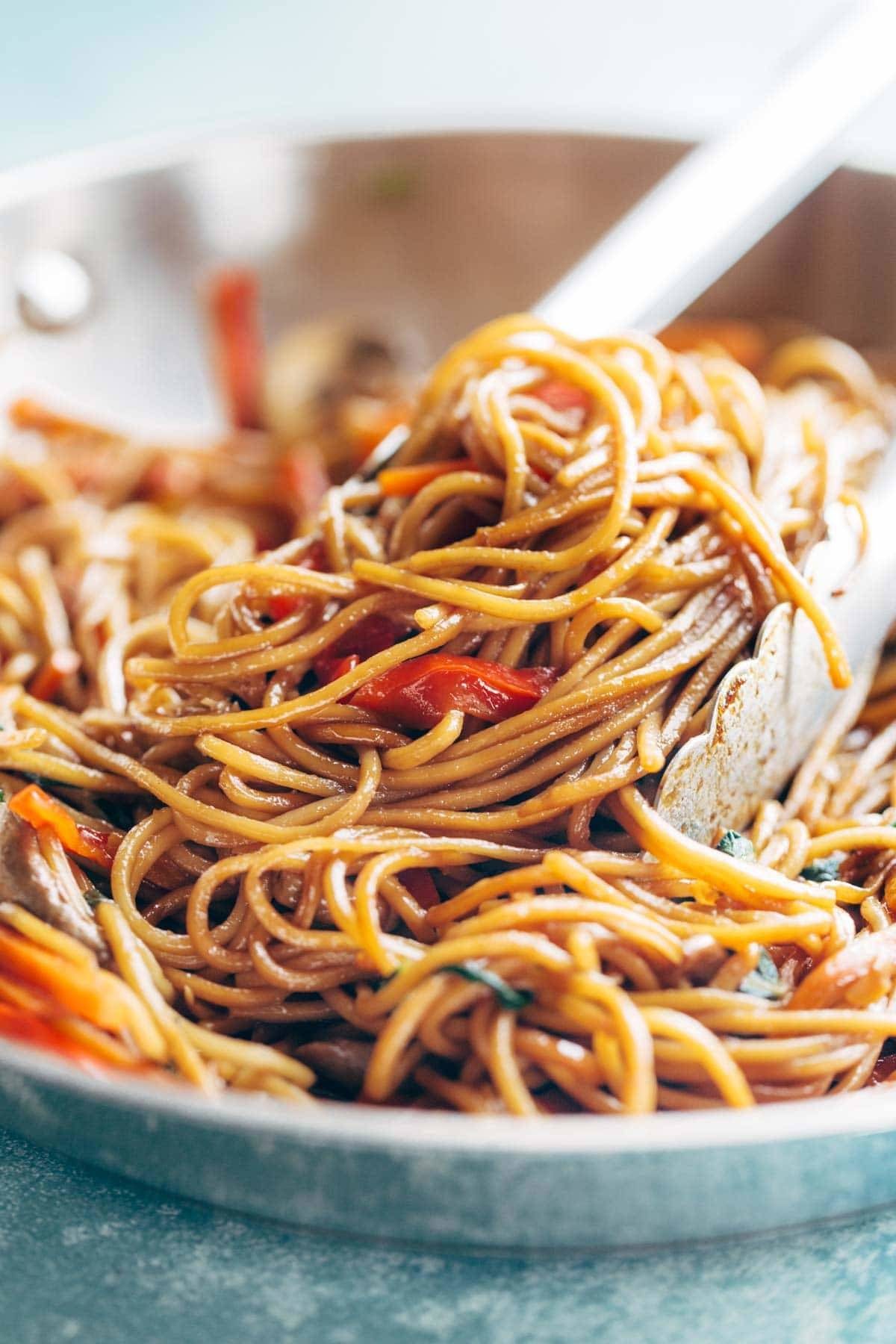 Tongs grabbing Lo Mein noodles.