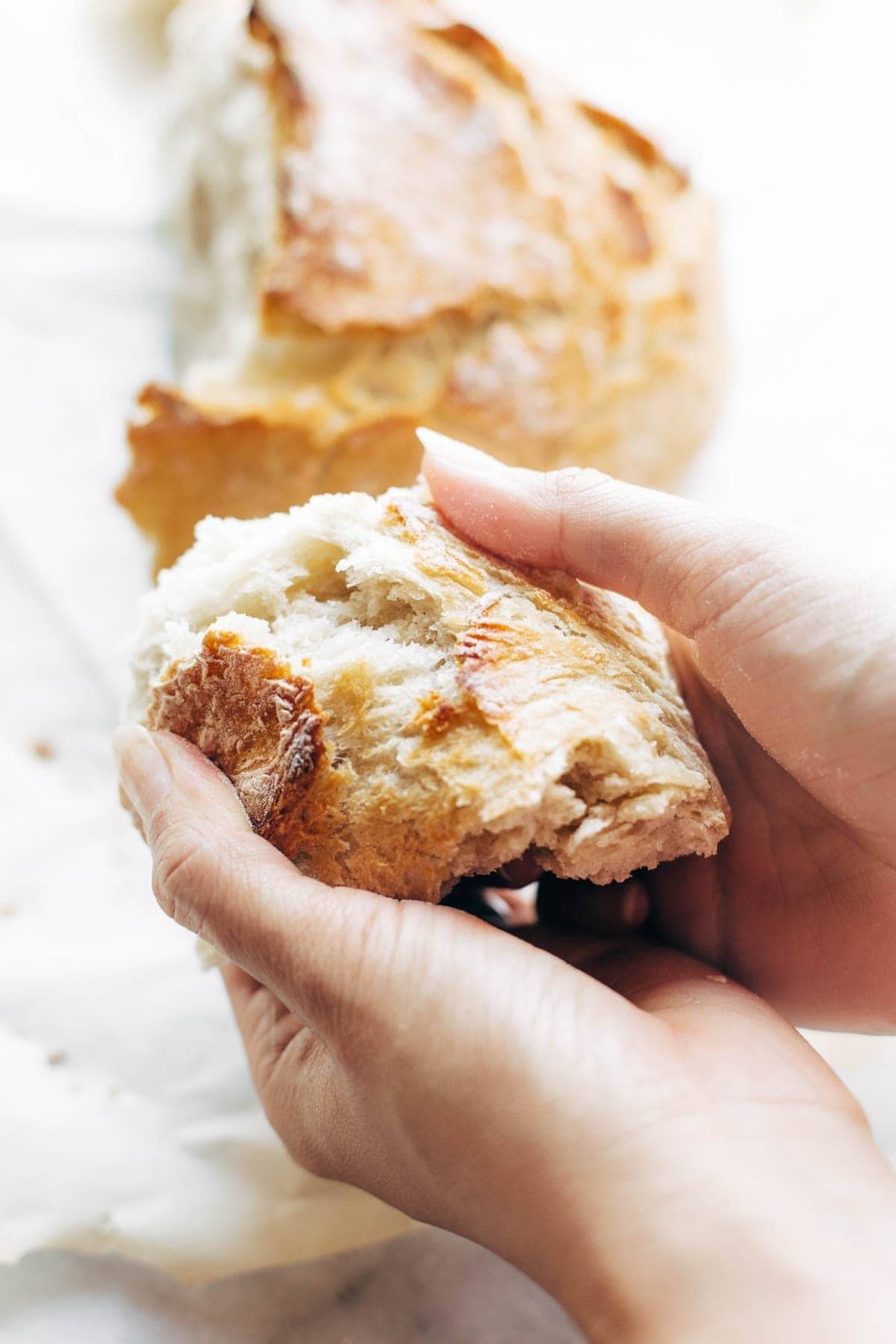 White hands tearing apart no knead bread.