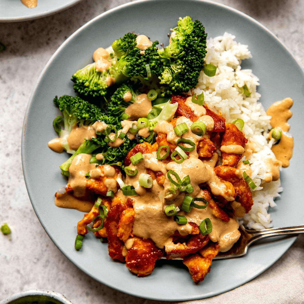 Red curry chicken in a bowl topped with cashew sauce.