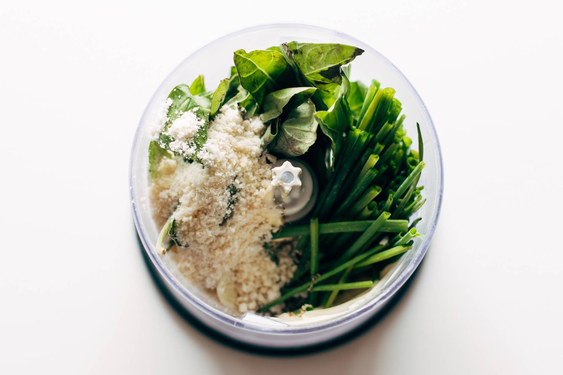 Ingredients for basil sauce in a food processor